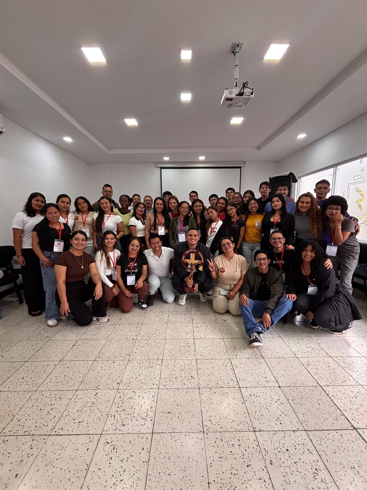 Foto de grupo de los jóvenes y servidores del seminario; uno de ellos sostiene una cruz con la frase Veni Creator Spiritus.